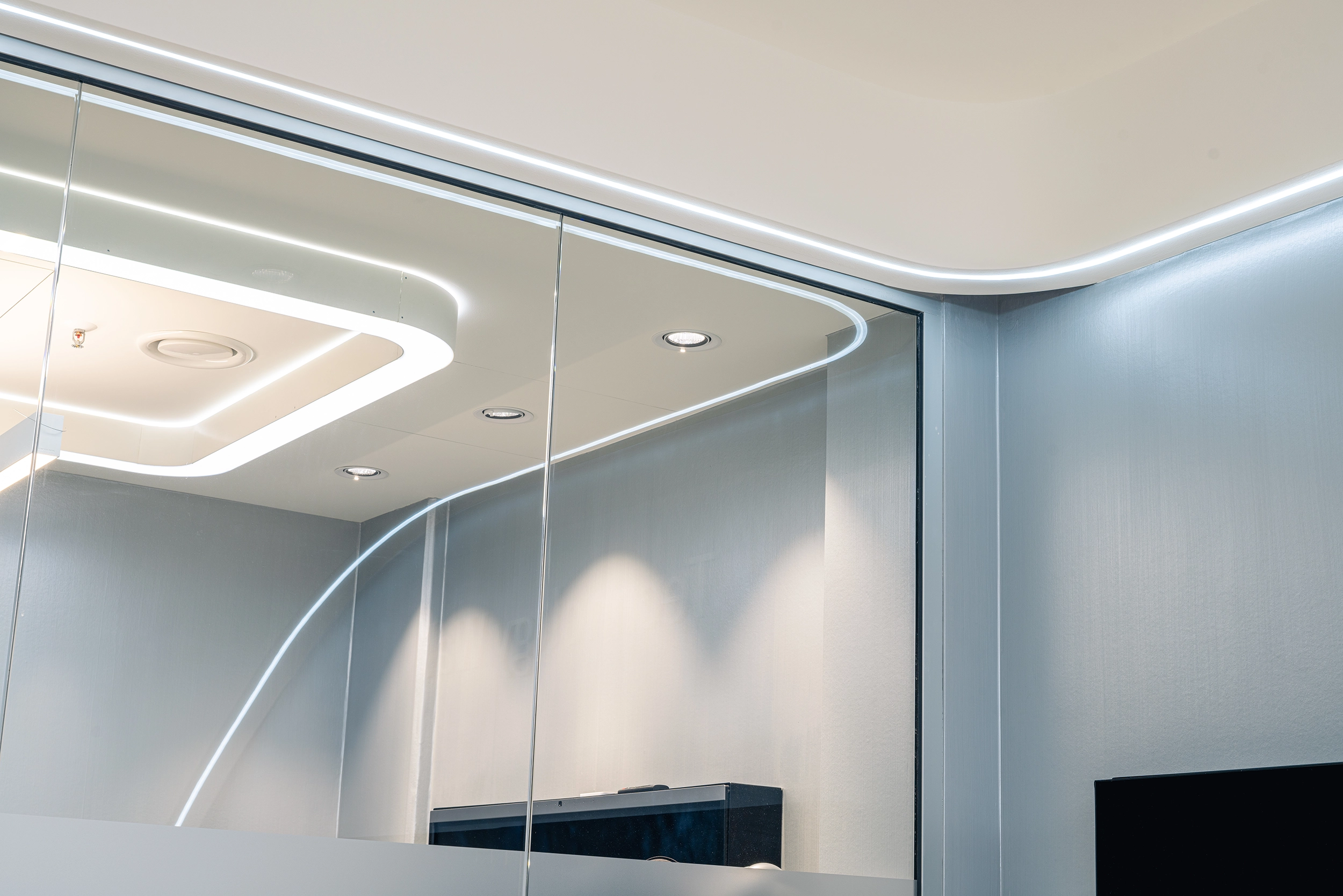 Detail of a modern BYD showroom interior with curved lighting and glass walls – automotive retail design by Vizona
