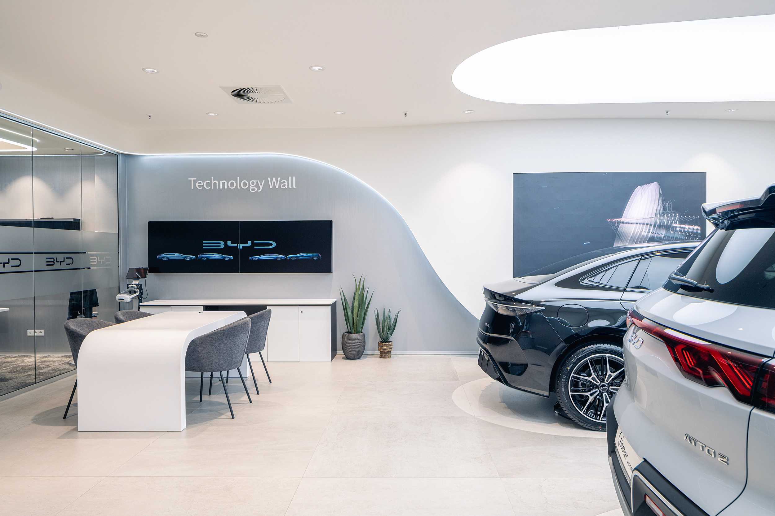 BYD showroom interior with lounge seating, digital screens and a white electric car – automotive retail design by Vizona