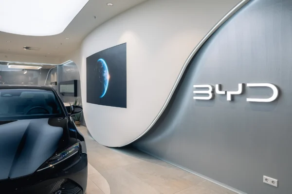 BYD dealership brand wall with a dark electric car in a Vizona-designed showroom – automotive retail interior