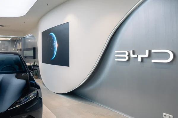 BYD brand logo wall with a dark electric car in the Vizona-designed dealership showroom – automotive retail design