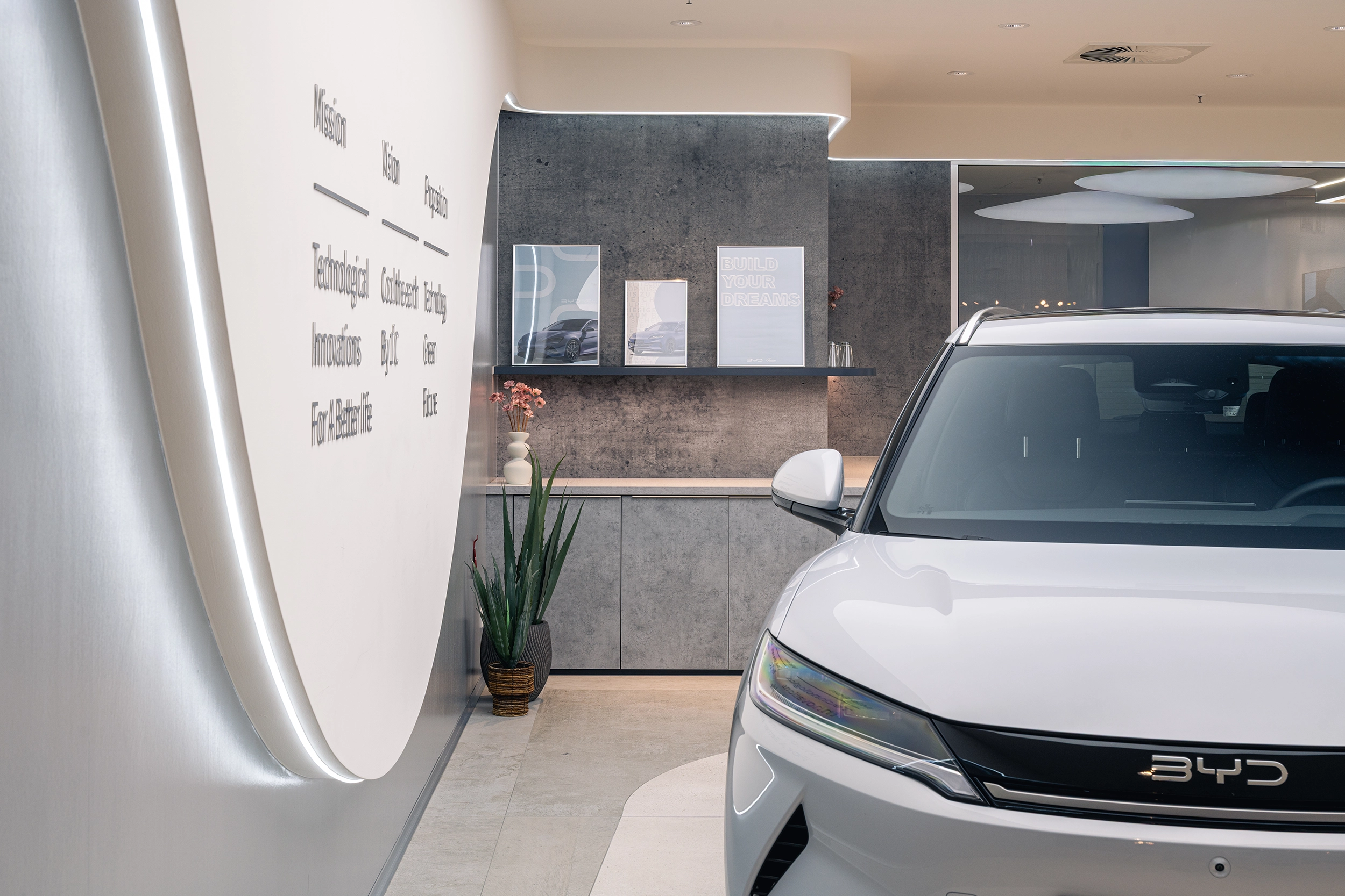 BYD car dealership showroom in Neumarkt with backlit brand wall and a displayed electric car – automotive retail design by Vizona